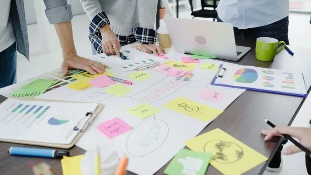 Pessoas reunidas na mesa com papéis sobre um projeto